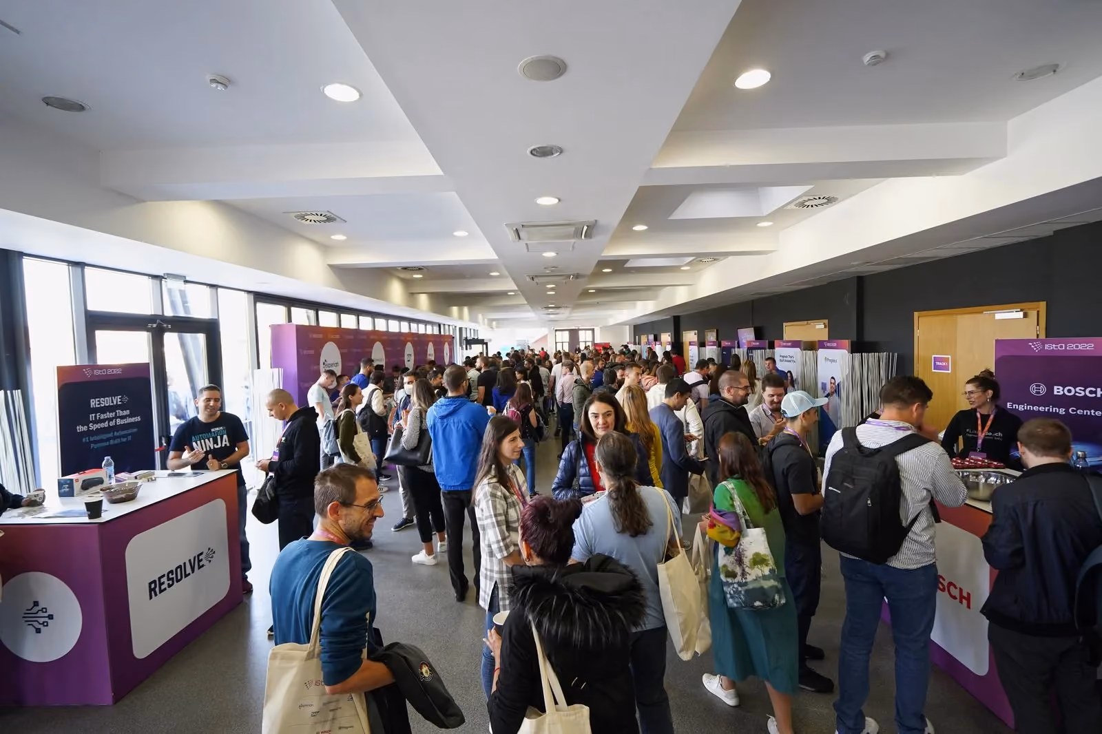 Attendees crowding the ISTA 2022 expo corridor between the Resolve and Bosch Engineering Center stands, several carrying ISTA tote bags.